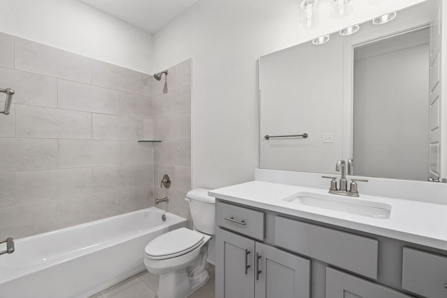 Bathroom featuring washtub / shower combination, vanity, and light tile patterned floors