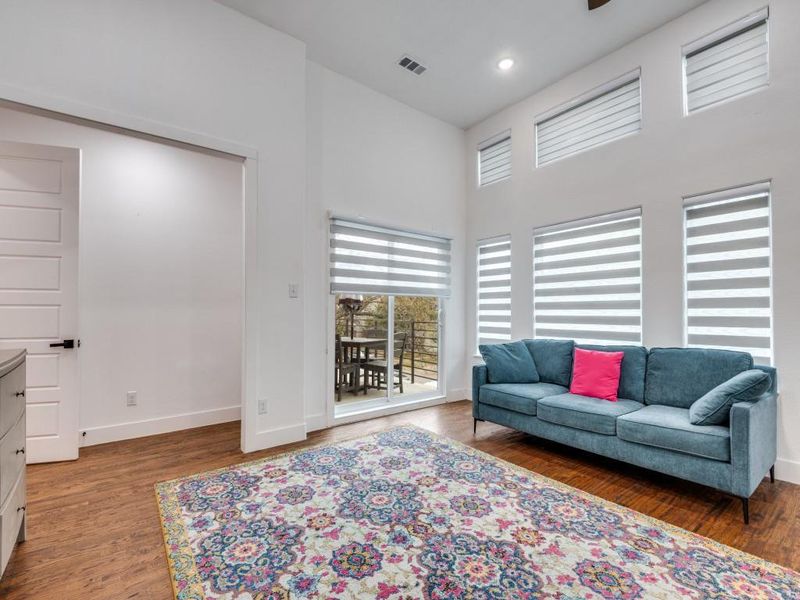 Primary bedroom featuring high ceilings, wood finished floors, recessed lighting and private patio.