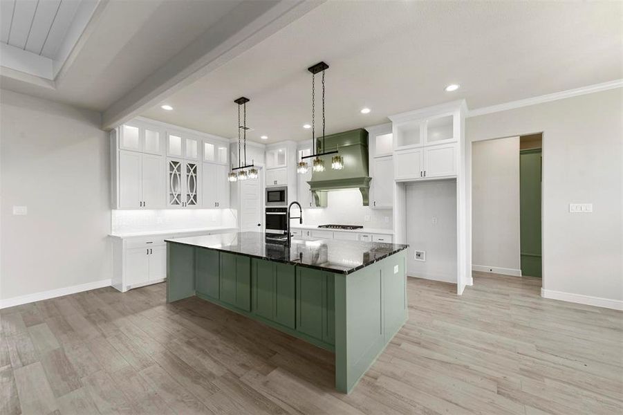 Kitchen with a center island with sink, white cabinets, stainless steel appliances, and custom range hood