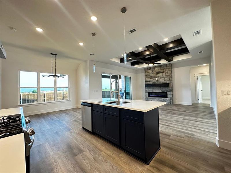 Kitchen featuring a sink, open floor plan, visible vents, coffered ceiling, and dishwasher