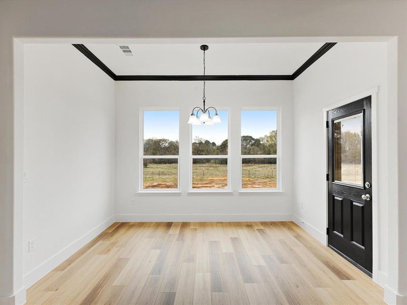 Unfurnished dining area featuring crown molding, light wood-style floors, plenty of natural light, and a chandelier Unfurnished dining area featuring crown molding, light wood-style floors, plenty of natural light, and a chandelier