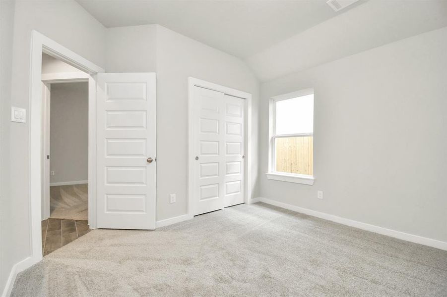 Secondary bedroom features plush carpeting, large windows that let in plenty of natural light, bright paint, and spacious closets.