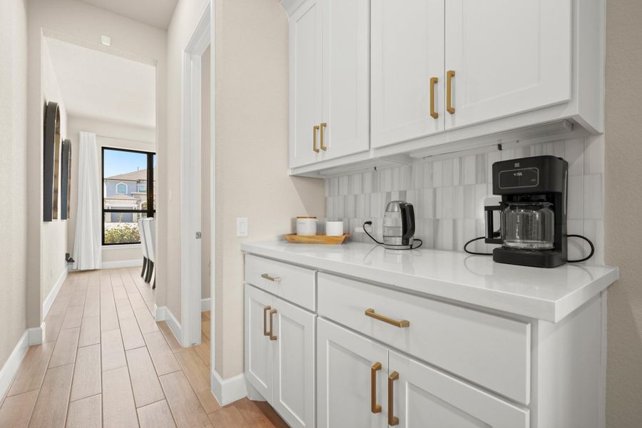 Bar with white cabinets, backsplash, light wood-style floors, and light stone counters Bar with white cabinets, backsplash, light wood-style floors, and light stone counters