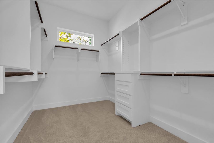 The primary bedroom includes a spacious walk-in closet with built-in shelves and carpeted flooring, providing ample storage and organization. The primary bedroom includes a spacious walk-in closet with built-in shelves and carpeted flooring, providing ample storage and organization.