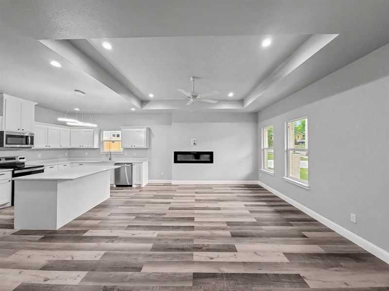 Kitchen with stainless steel appliances, a raised ceiling, a sink, recessed lighting, and light wood finished floors Kitchen with stainless steel appliances, a raised ceiling, a sink, recessed lighting, and light wood finished floors