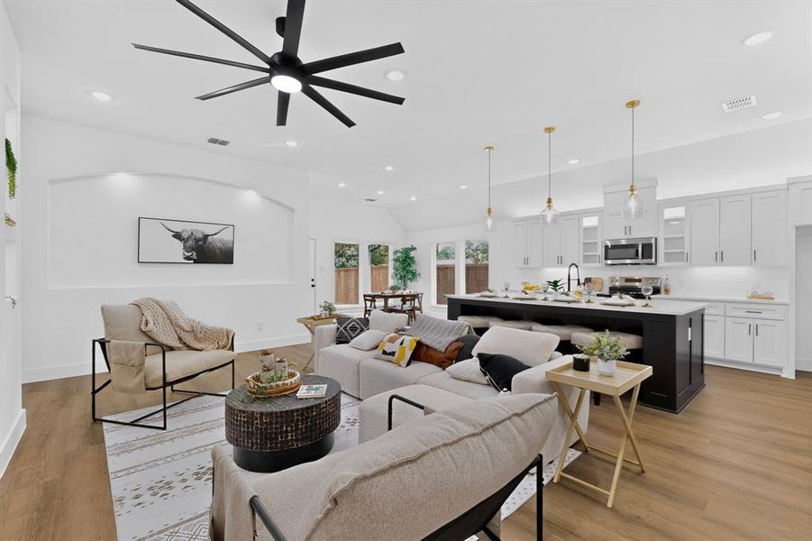 Open-concept living space featuring wood-finish flooring, a contemporary ceiling fan, recessed lighting, and an arched wall niche