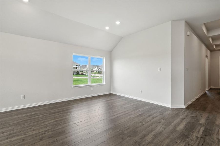 Empty room with dark wood-style floors, vaulted ceiling, and recessed lighting