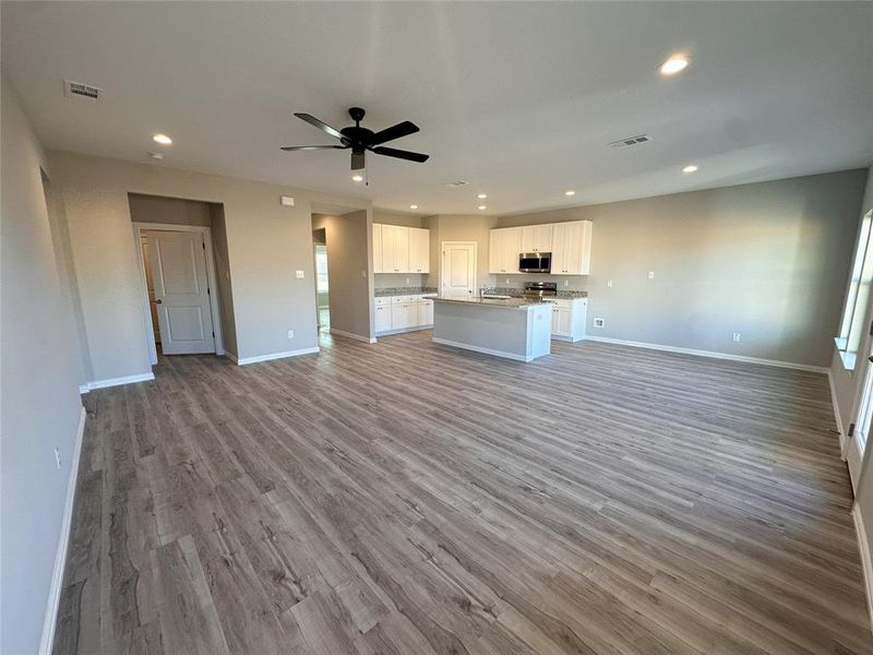 Unfurnished living room featuring wood-type flooring and ceiling fan