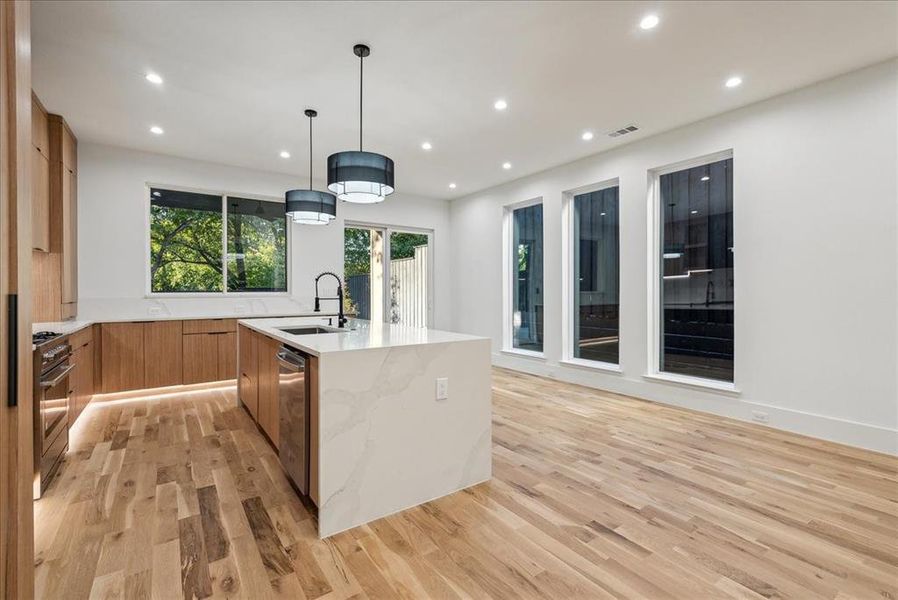 Kitchen featuring light hardwood / wood-style floors, a center island with sink, pendant lighting, and sink