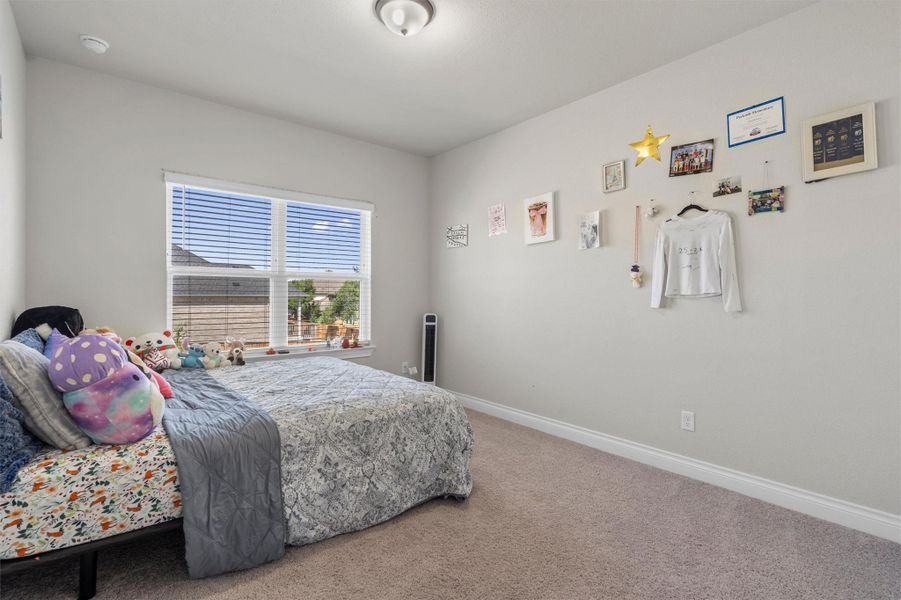 Plush wall-to-wall carpeting and a wide window with integrated blinds anchor this comfortable space.