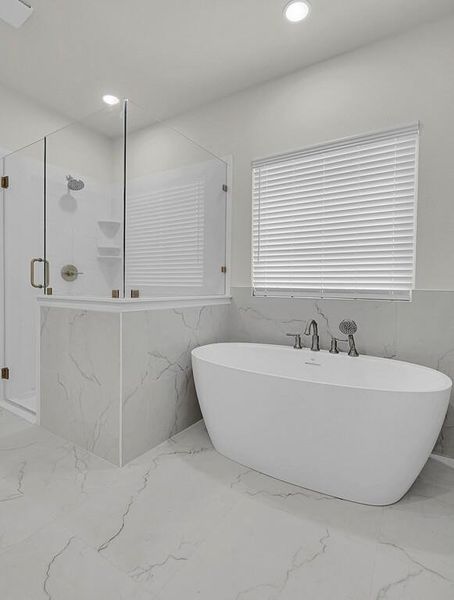 Bathroom featuring marble tiled flooring, a marble finish shower, a freestanding tub, recessed lighting, and tile walls