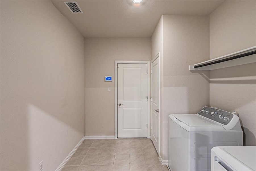 Laundry room with visible vents, baseboards, washer and clothes dryer, light tile patterned floors, and laundry area