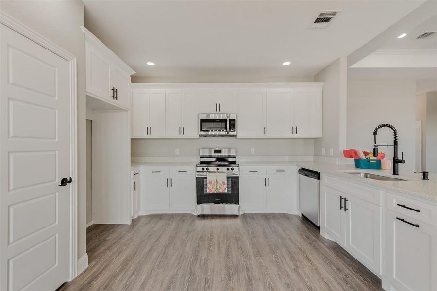 Kitchen featuring white cabinetry, appliances with stainless steel finishes, sink, and light hardwood / wood-style flooring