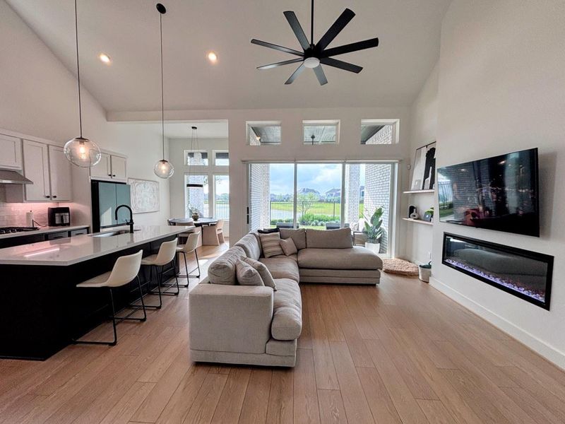 Open-concept living space features a modern kitchen with a large island, pendant lighting, and sleek white cabinetry.