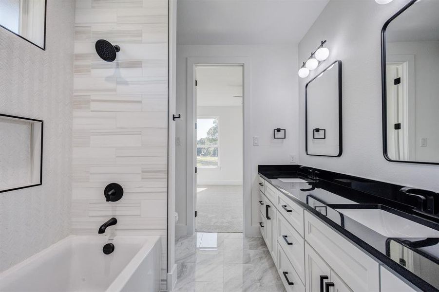 Bathroom featuring a dual vanity with black countertops, white cabinetry, and matte black hardware Bathroom featuring a dual vanity with black countertops, white cabinetry, and matte black hardware
