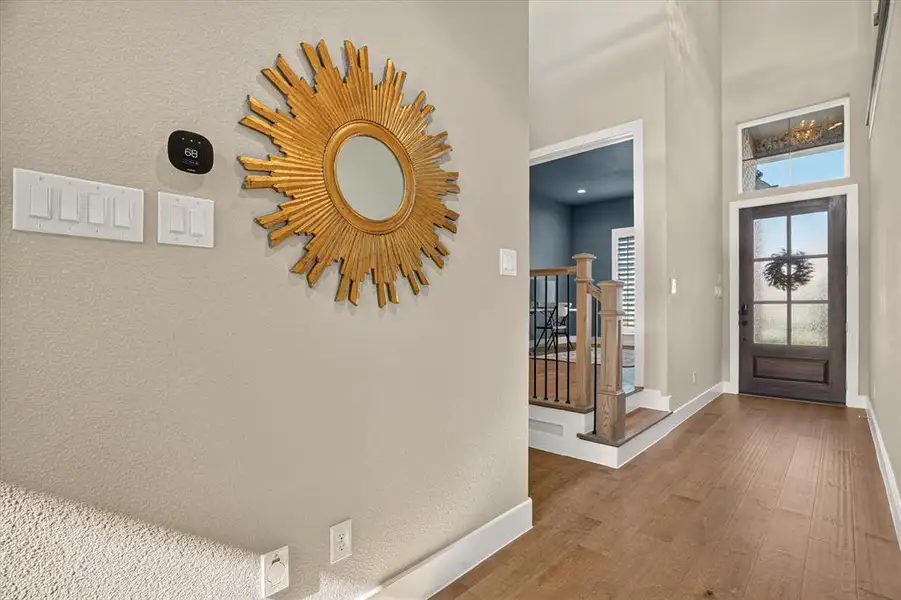 Entryway featuring wood-finish flooring, a dark wood-finish front door with frosted glass panels, and a transom window above Entryway featuring wood-finish flooring, a dark wood-finish front door with frosted glass panels, and a transom window above
