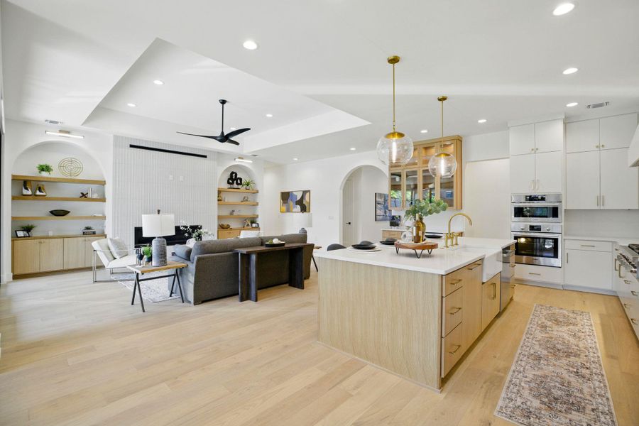 Kitchen featuring a ceiling fan, light wood-style floors, appliances with stainless steel finishes, built in shelves, and arched walkways