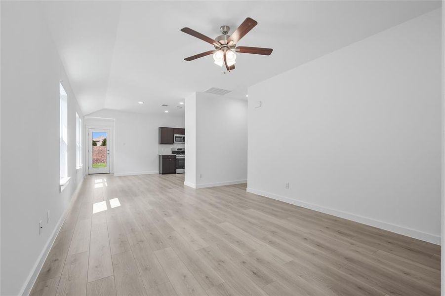 Unfurnished living room with light wood-style floors, a ceiling fan, recessed lighting, and lofted ceiling Unfurnished living room with light wood-style floors, a ceiling fan, recessed lighting, and lofted ceiling