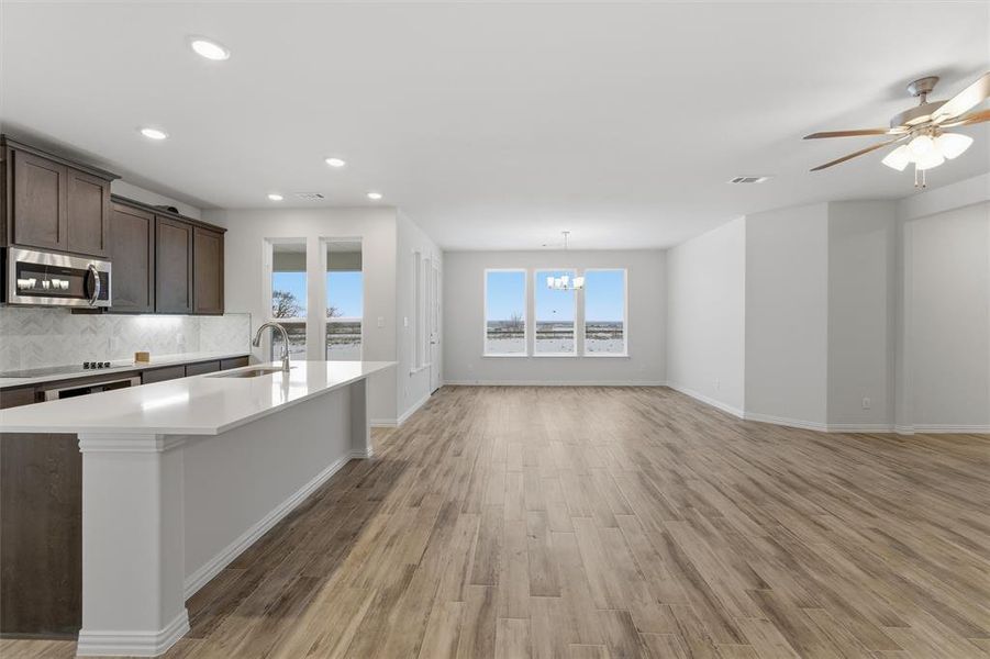 Kitchen with light wood-type flooring, dark brown cabinetry, an island with sink, stainless steel appliances, and a chandelier Kitchen with light wood-type flooring, dark brown cabinetry, an island with sink, stainless steel appliances, and a chandelier