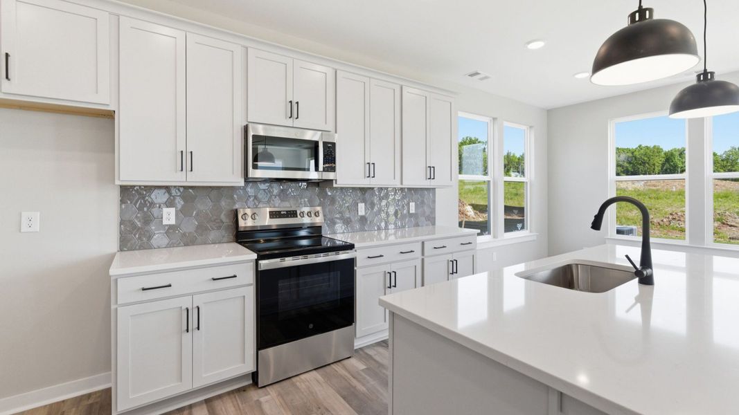 Kitchen with tile backsplash, pendant lighting, and quartz countertops