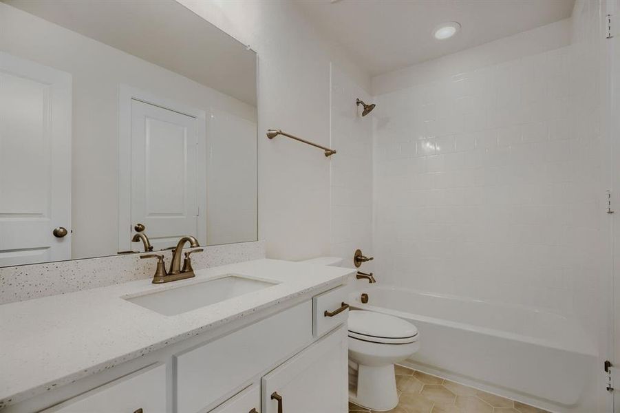 Bathroom featuring a spacious vanity with an integrated sink, a large wall-mounted mirror, and white cabinetry with dark hardware