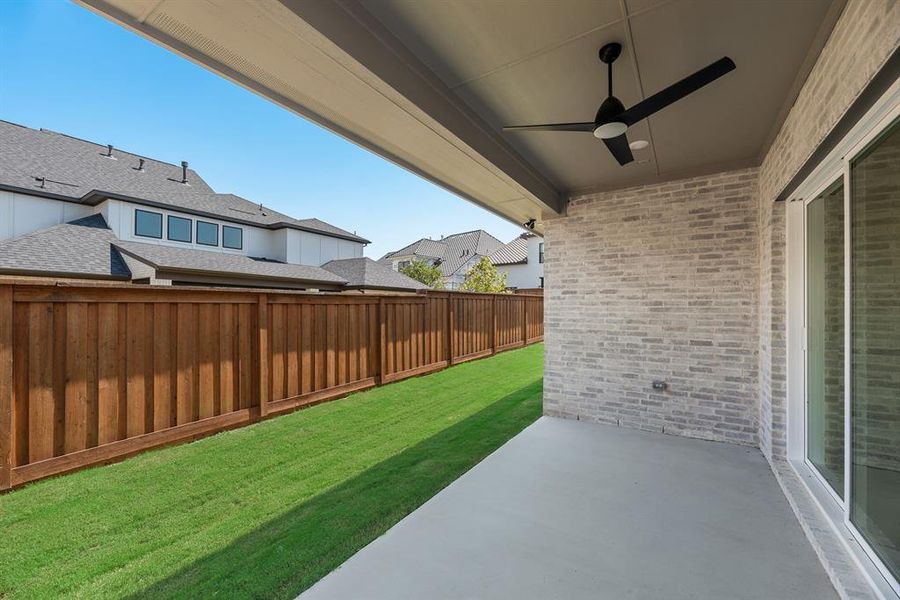 Fenced backyard featuring ceiling fan and a patio
