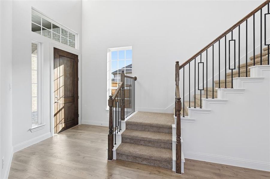 Entrance foyer featuring a towering ceiling, light wood-style flooring, and stairs