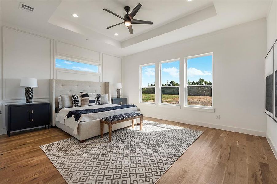 Bedroom featuring a raised ceiling, ceiling fan, and wood-type flooring