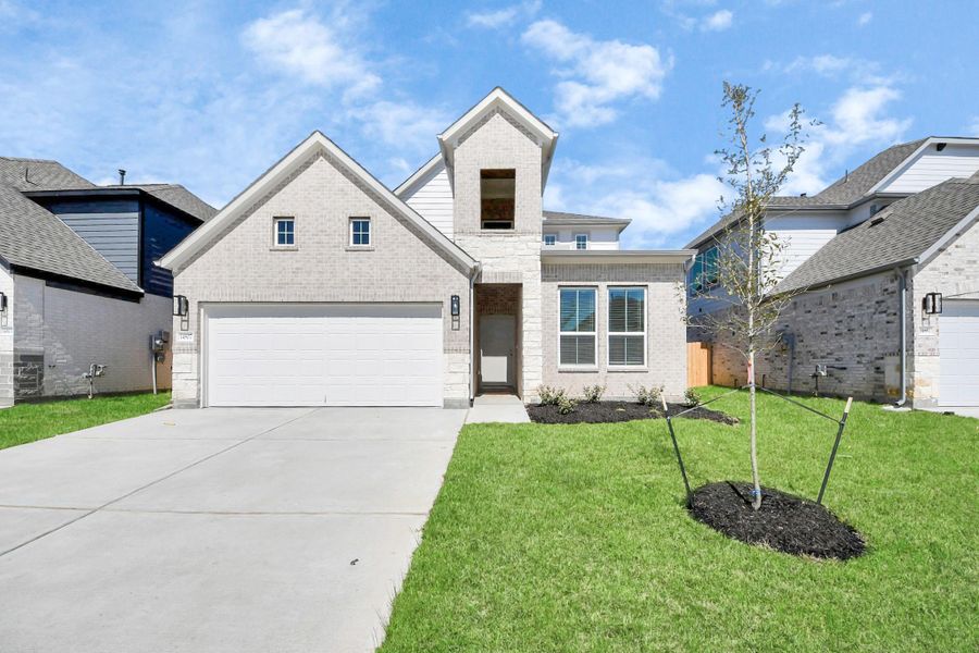 Behold a lush landscape, impeccably maintained yard, and a premium elevation adorned with captivating brick and stone features.