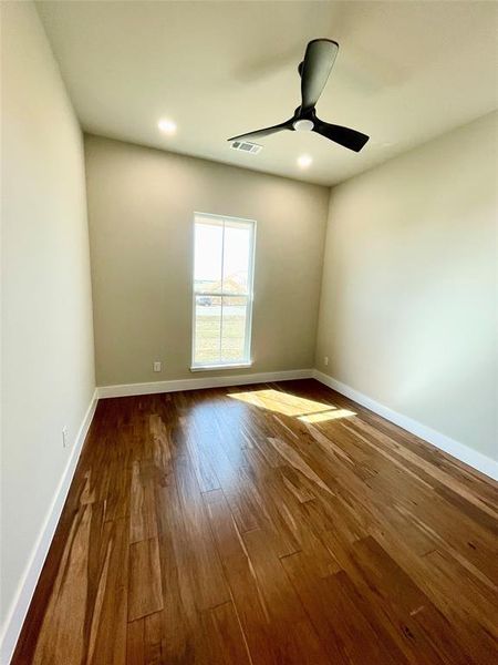 Third bedroom with dark wood finished floors and ceiling fan