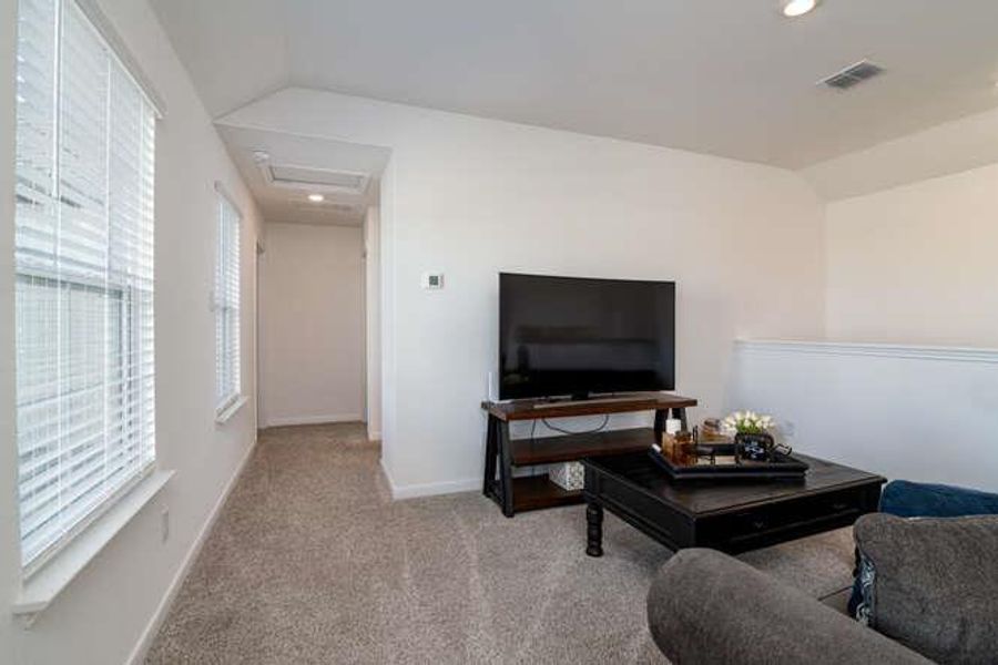 Carpeted living area with lofted ceiling, attic access, and recessed lighting