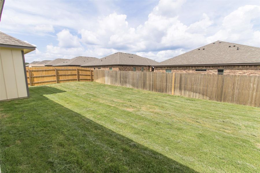 A well-maintained lawn offers ample space for outdoor enjoyment, fully enclosed by fencing.
