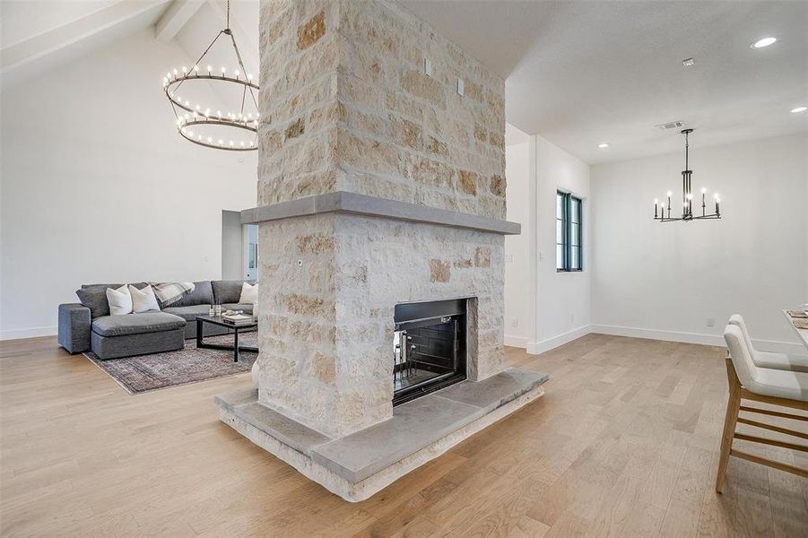 Living room featuring beamed ceiling, high vaulted ceiling, a fireplace, and light wood-type flooring