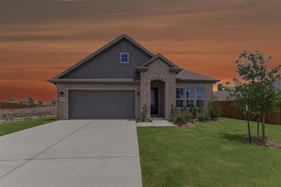 Brick and shingle exterior featuring an arched entryway, attached two-car garage, and a manicured front lawn with a young tree Brick and shingle exterior featuring an arched entryway, attached two-car garage, and a manicured front lawn with a young tree