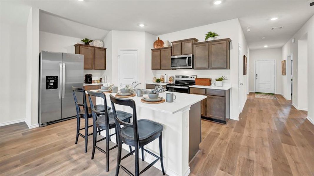 Kitchen with stainless steel appliances, a kitchen breakfast bar, a kitchen island with sink, dark wood finish cabinetry, and recessed lighting