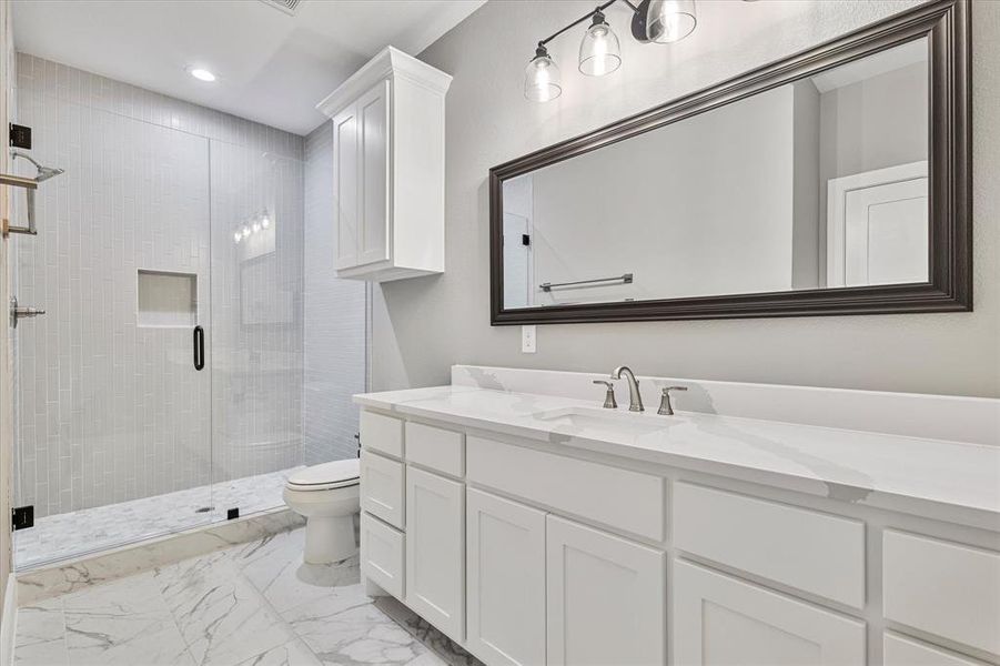 Bathroom with tile patterned flooring, an enclosed shower, vanity, and toilet