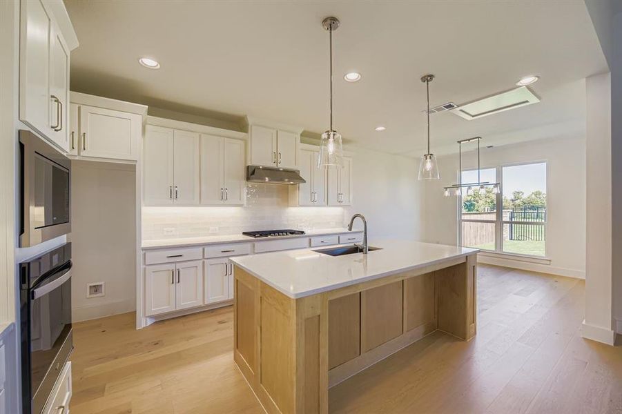 Kitchen with tasteful backsplash, white cabinets, light wood-style floors, recessed lighting, and stainless steel appliances