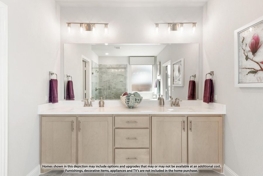 Bathroom with double vanity, light wood cabinets, white countertops, and large mirror with wall sconces