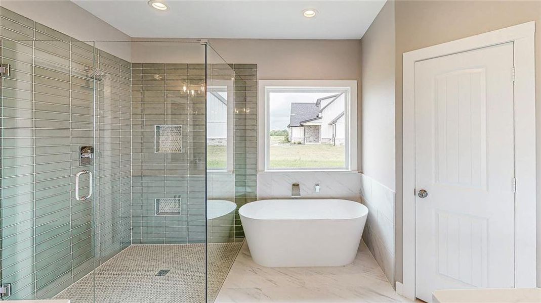 Ensuite bath with large walk in frameless glass shower with mud pan. Designer tile with built in soap ledge