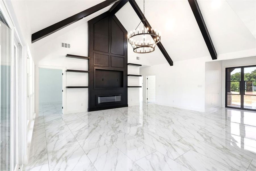 Spacious room featuring a vaulted ceiling with exposed beams, a built-in dark wood media wall with an electric fireplace, marble-look tile flooring, and a large chandelier