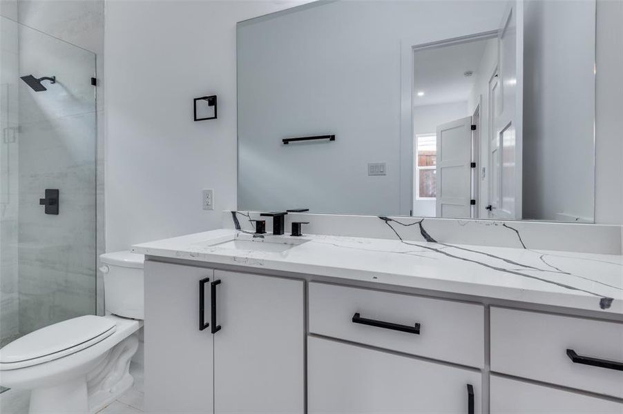 Bathroom with toilet, vanity, walk in shower, and tile patterned floors