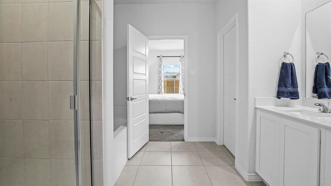 Full bath with vanity, ensuite bath, a stall shower, and light tile patterned flooring