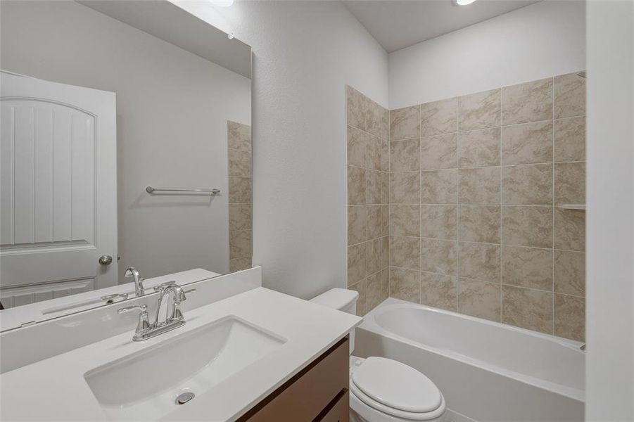 Bathroom featuring a built-in bathtub with tiled surround, a single vanity with an integrated sink and chrome faucet, and a large wall-mounted mirror Bathroom featuring a built-in bathtub with tiled surround, a single vanity with an integrated sink and chrome faucet, and a large wall-mounted mirror
