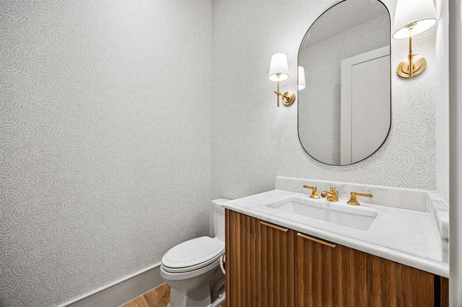 Contemporary vanity with a wood-finish base and integrated sink, complemented by a white countertop and gold-finish fixtures Contemporary vanity with a wood-finish base and integrated sink, complemented by a white countertop and gold-finish fixtures