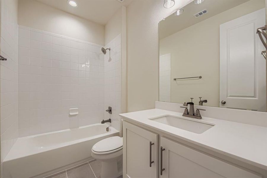 Full bathroom featuring shower / bath combination, vanity, dark tile patterned floors, and recessed lighting