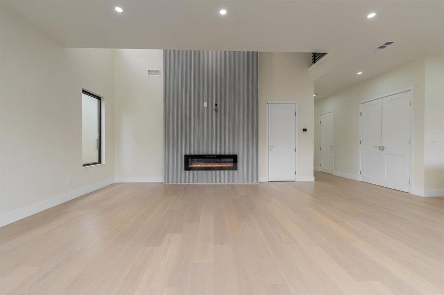 Family room with recessed lighting, a large fireplace, and light wood-style flooring
