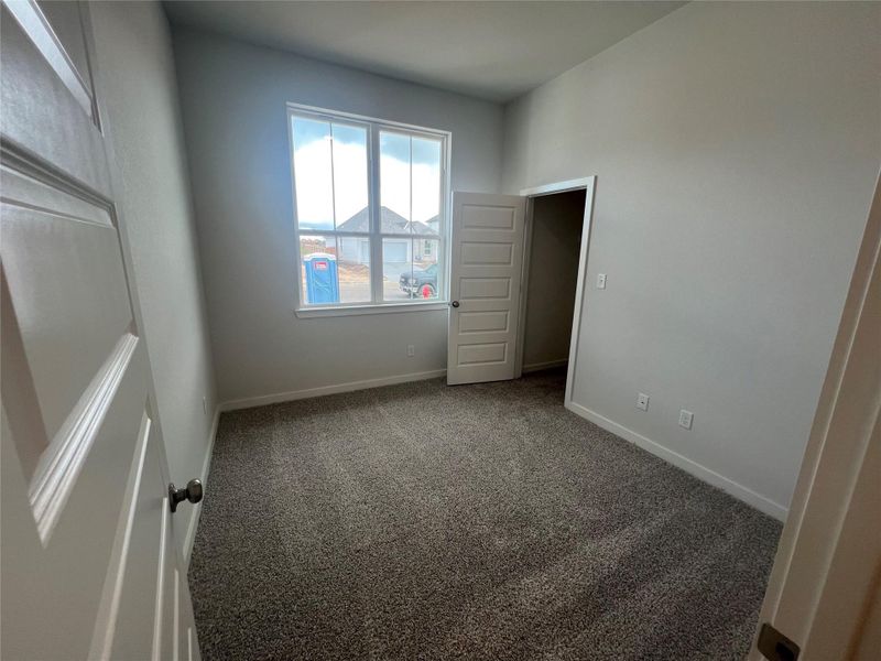 A well-lit room awaits your personal touch, featuring soft carpet and ample natural light.