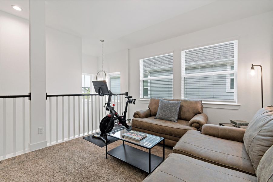 Cozy and bright loft area featuring plush seating, abundant natural light from multiple windows, and space for a personal exercise zone. Cozy and bright loft area featuring plush seating, abundant natural light from multiple windows, and space for a personal exercise zone.