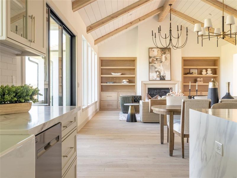 Dining room featuring a glass covered fireplace, healthy amount of natural light, light wood-style floors, beam ceiling, and high vaulted ceiling