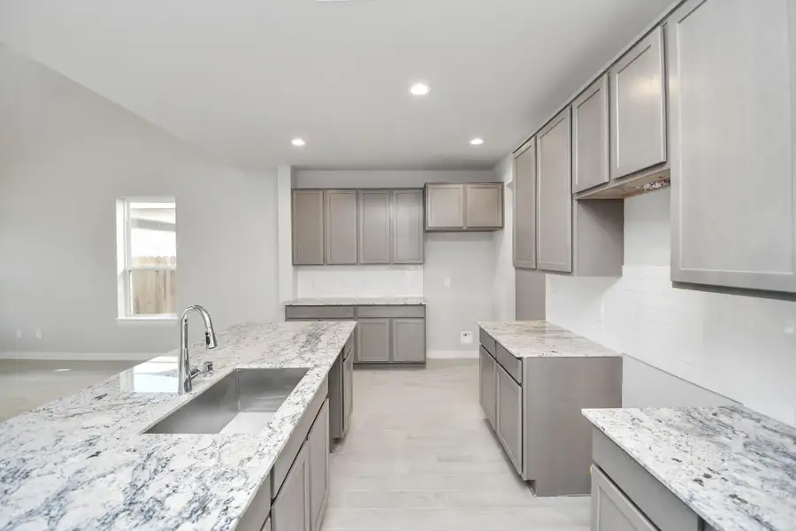 Step into a dream realized with this generously spacious kitchen! A massive granite island takes center stage, complemented by high ceilings, soft-close cabinets, granite countertops, stainless steel appliances, a sleek tile backsplash, and recessed lighting. Sample photo of completed home with similar floor plan. Actual colors and selections may vary.